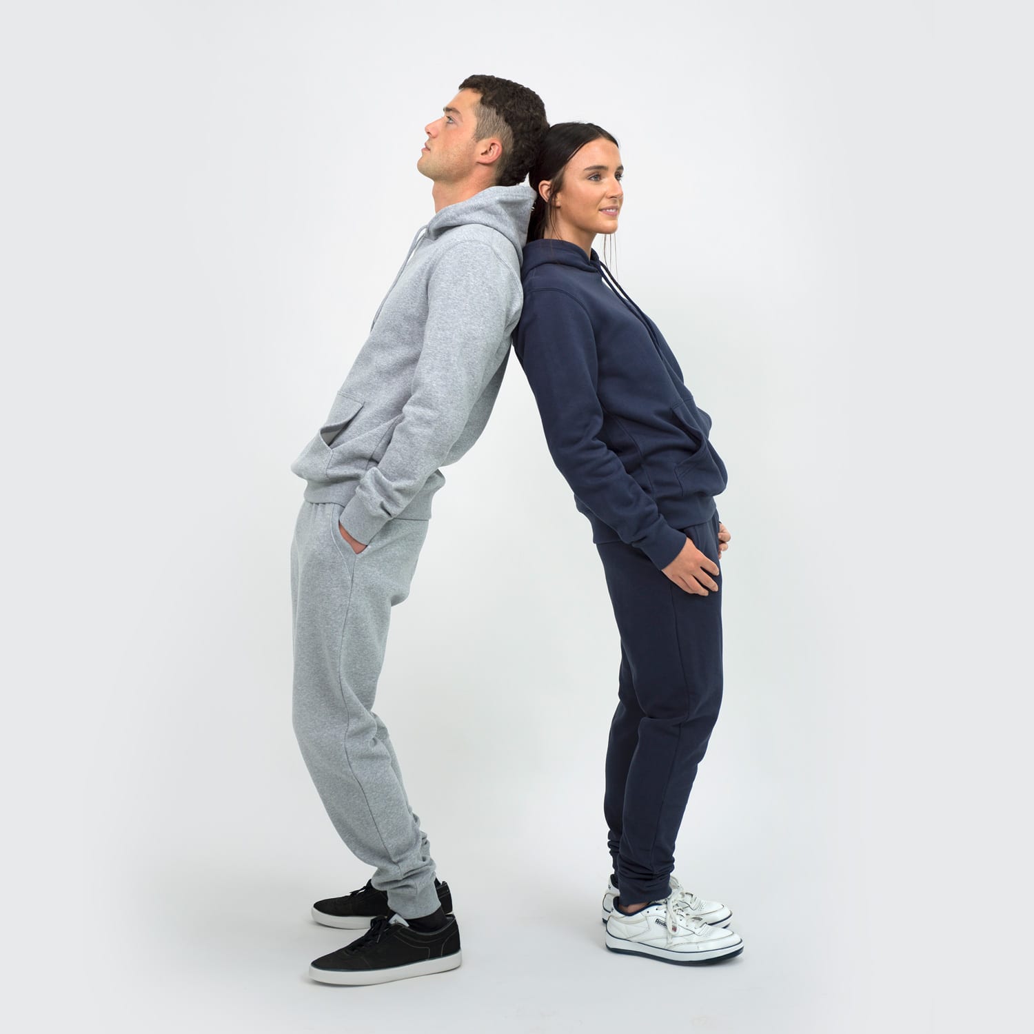 A unisex hoodie in grey and navy worn by two models, standing back to back, featuring a logo on the hood.