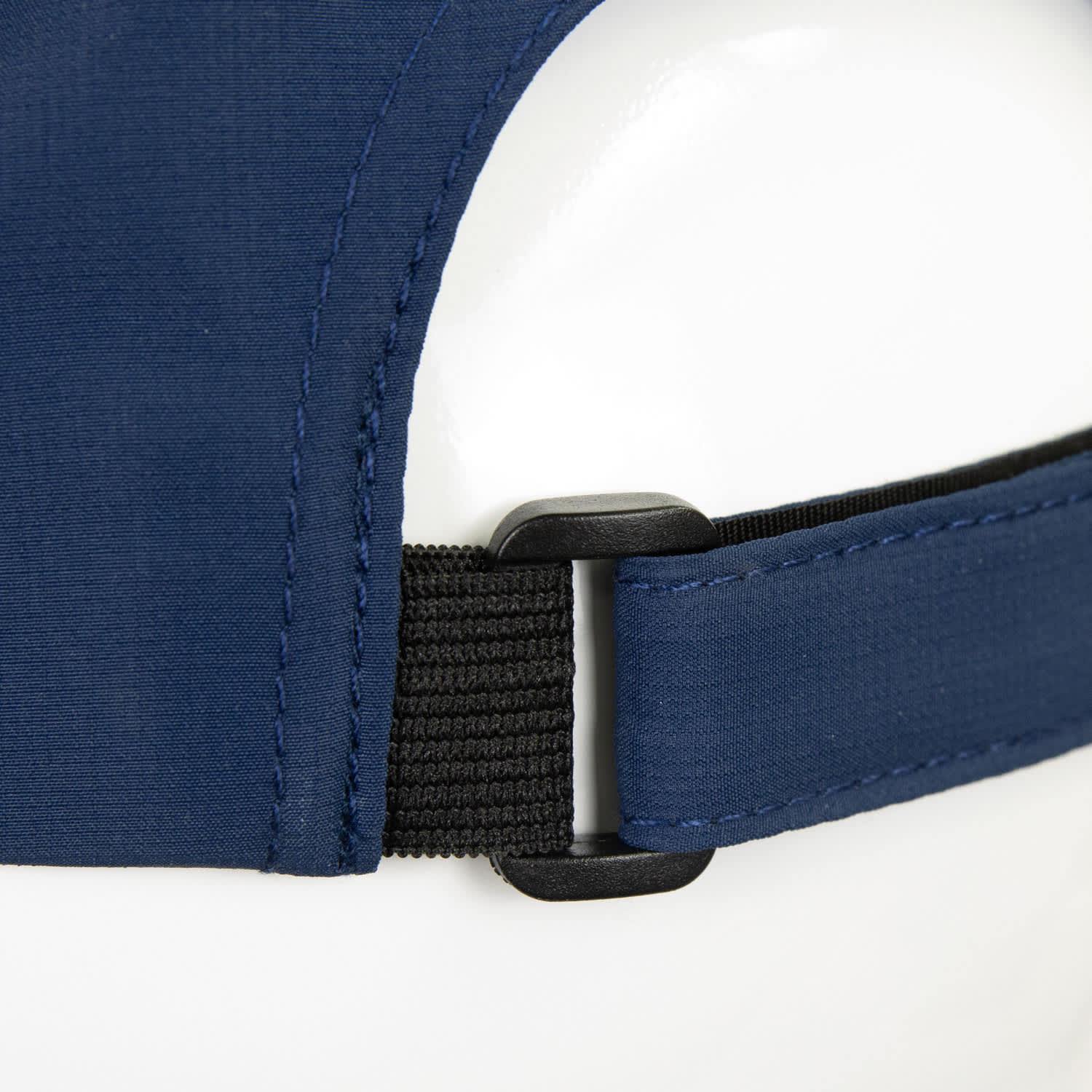 A navy cap featuring an adjustable strap with a plastic clasp and a smooth fabric finish.