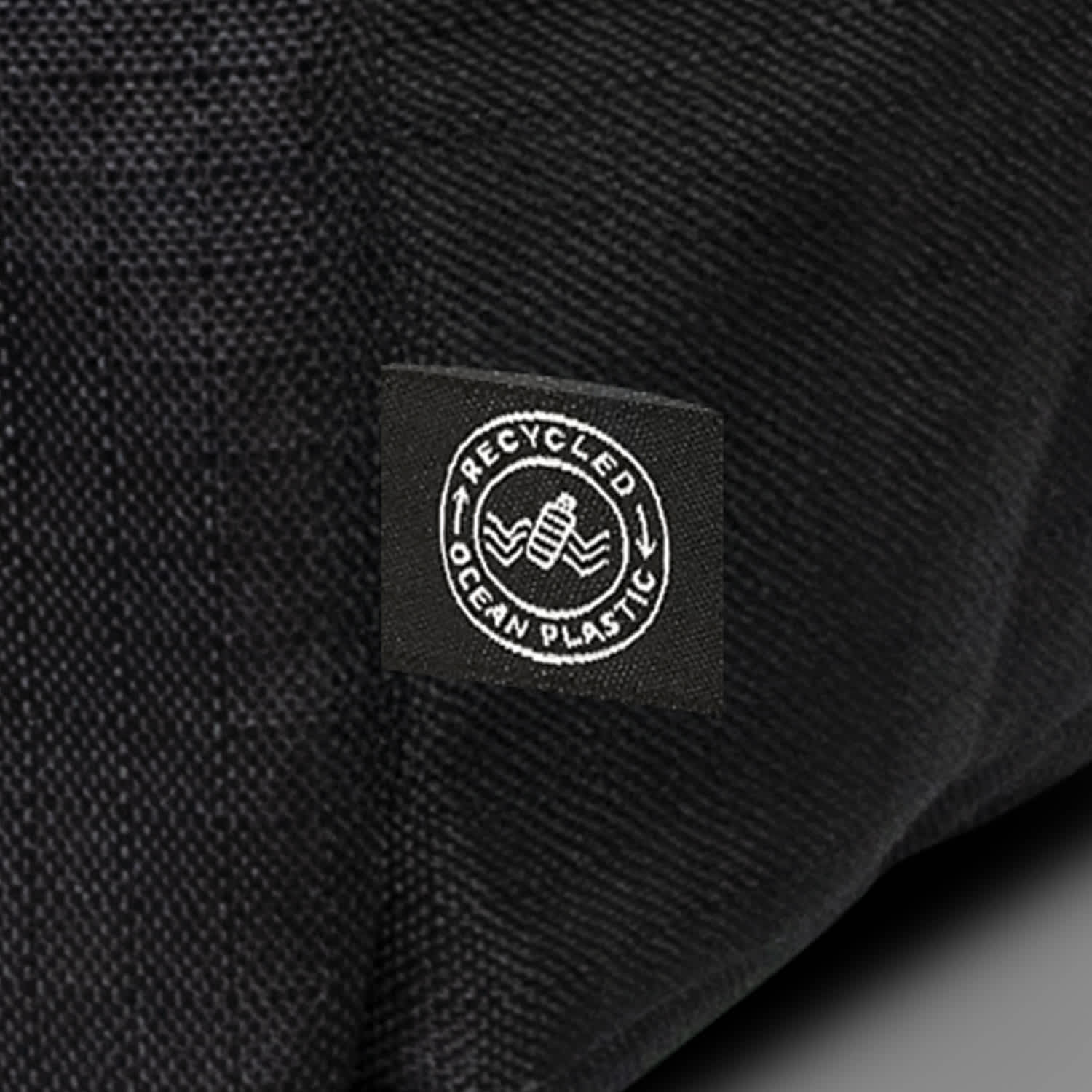 A black backpack made from recycled ocean plastic with a small logo patch.