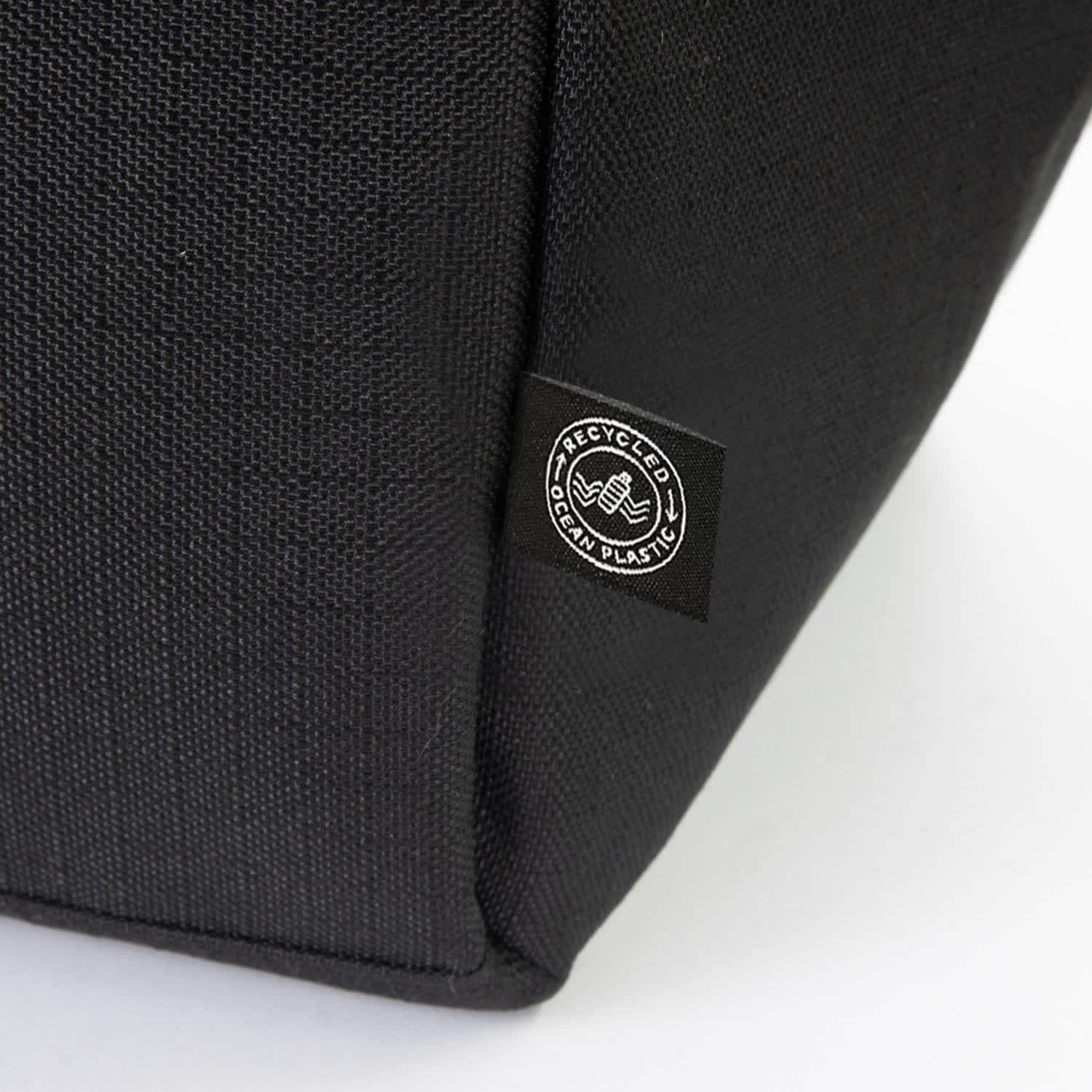 A black cooler bag featuring a logo, made from recycled materials. The textured fabric is visible in the image.