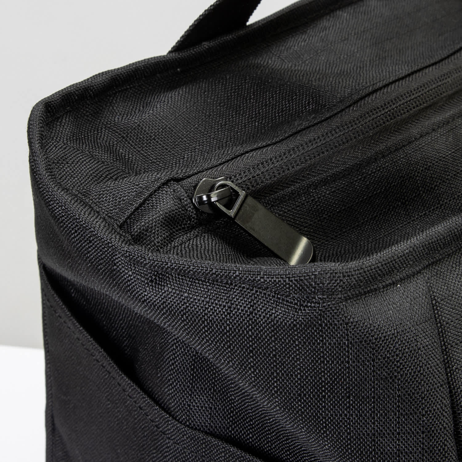 A black cooler bag with a zip closure and textured fabric, featuring an exterior pocket.