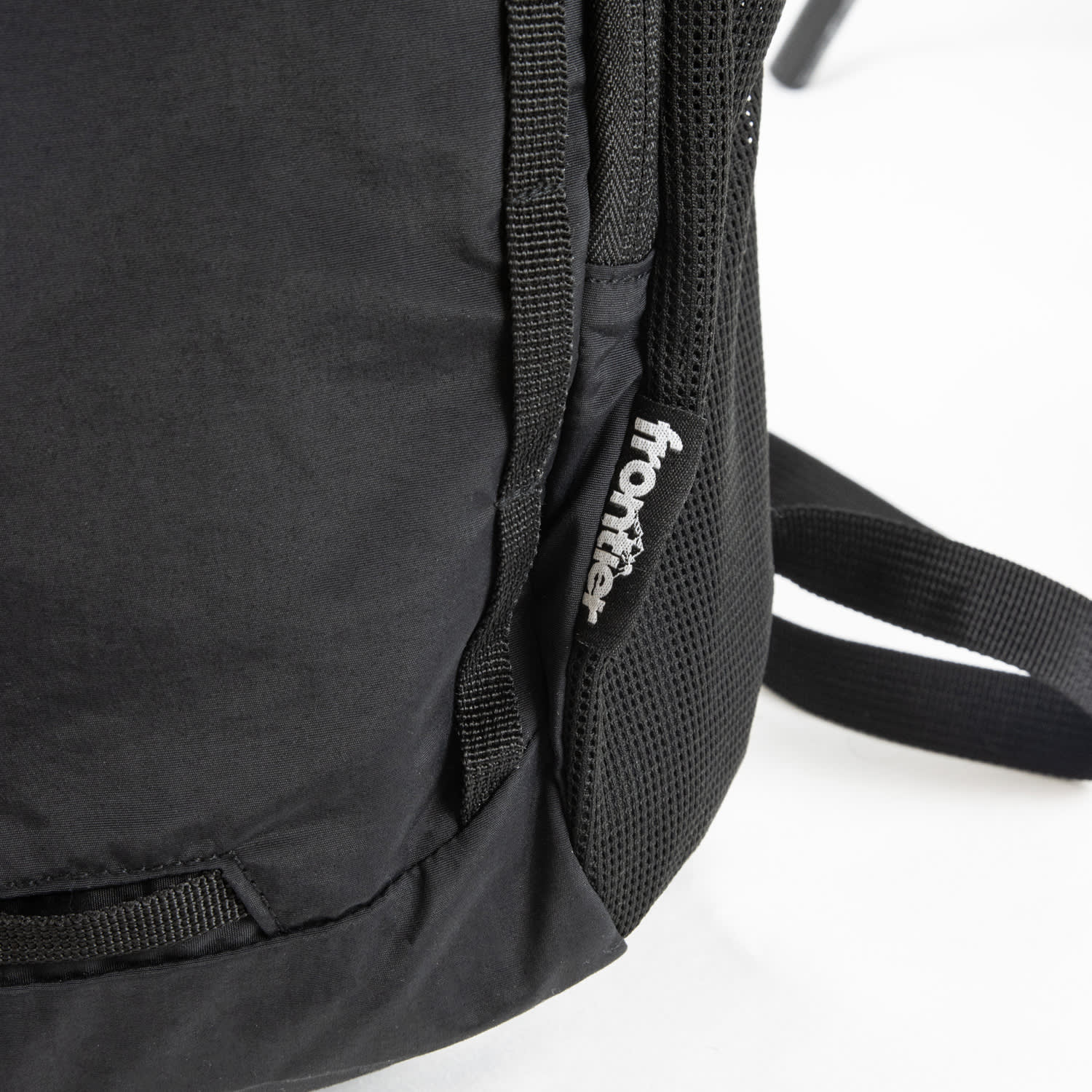 A black daypack with mesh detailing and a logo on the side. The straps are partially visible.