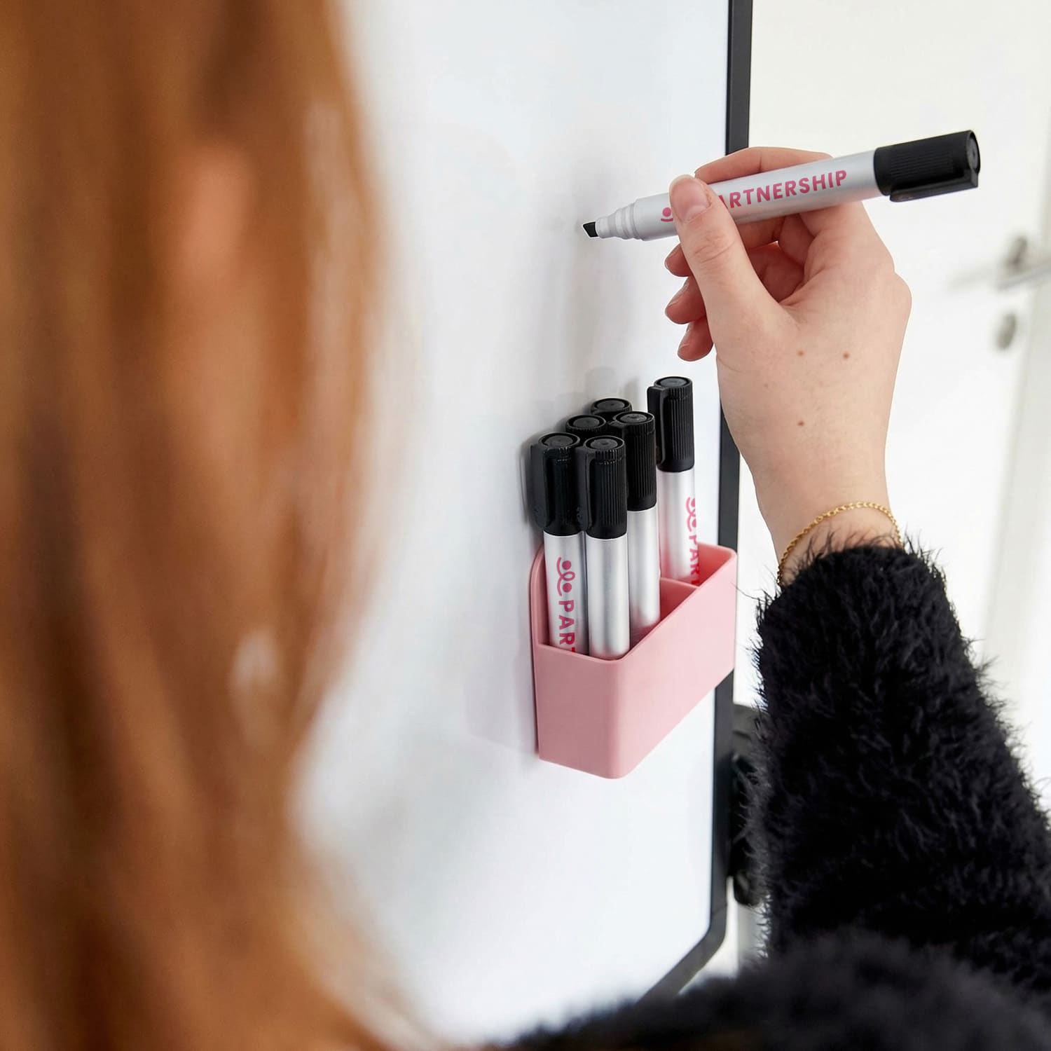 A collection of Staedtler Lumocolor whiteboard markers with chisel tips, featuring black and pink colours in a holder.
