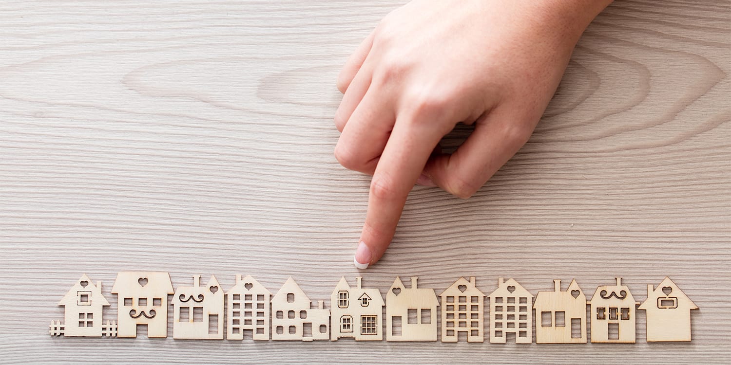 Finger pointing at house to fix and flip as investment