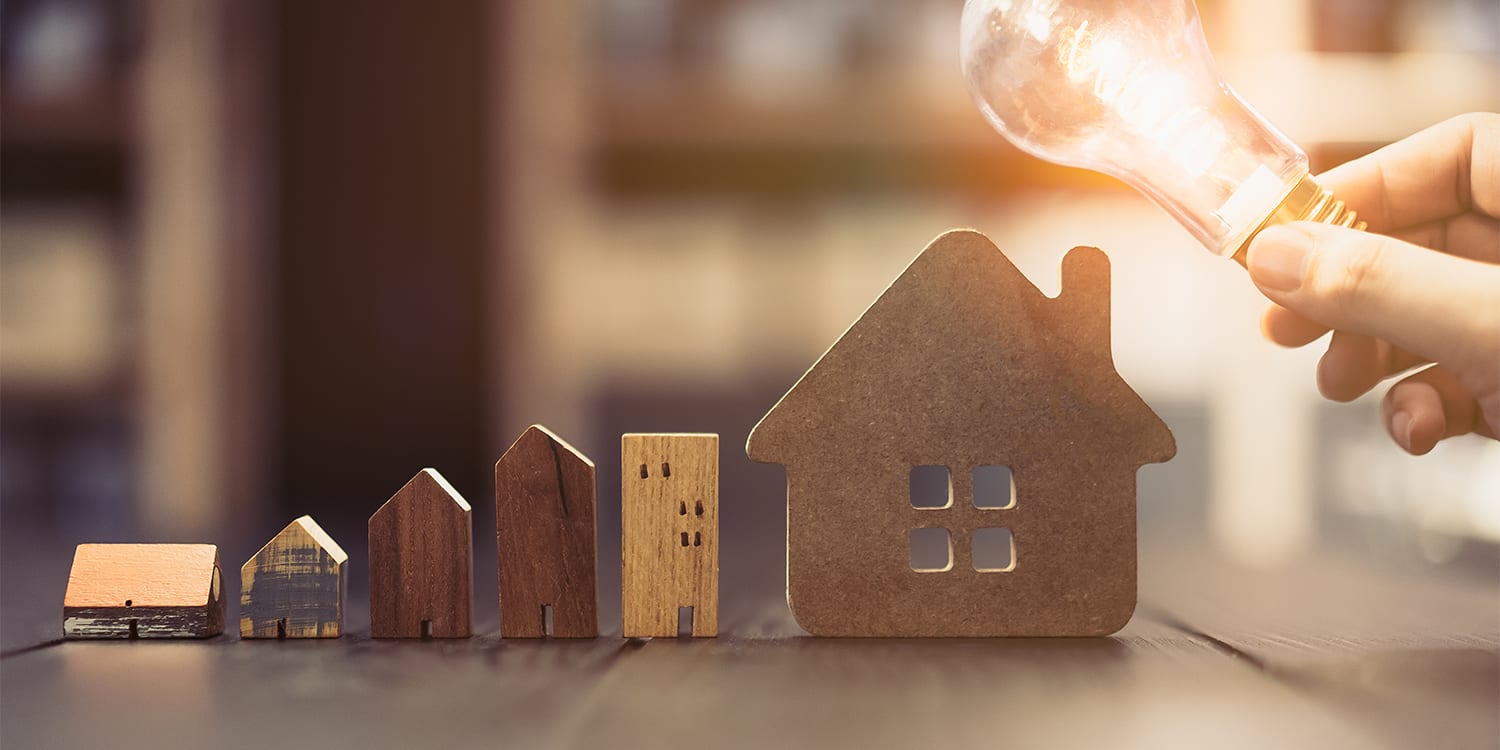 Wooden houses and lightbulb to represent real estate investment concept of buying probate properties