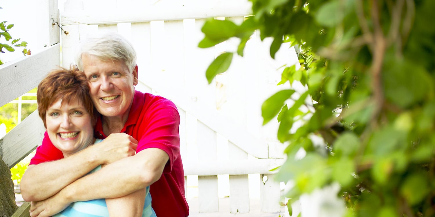 Happy older couple in front of house