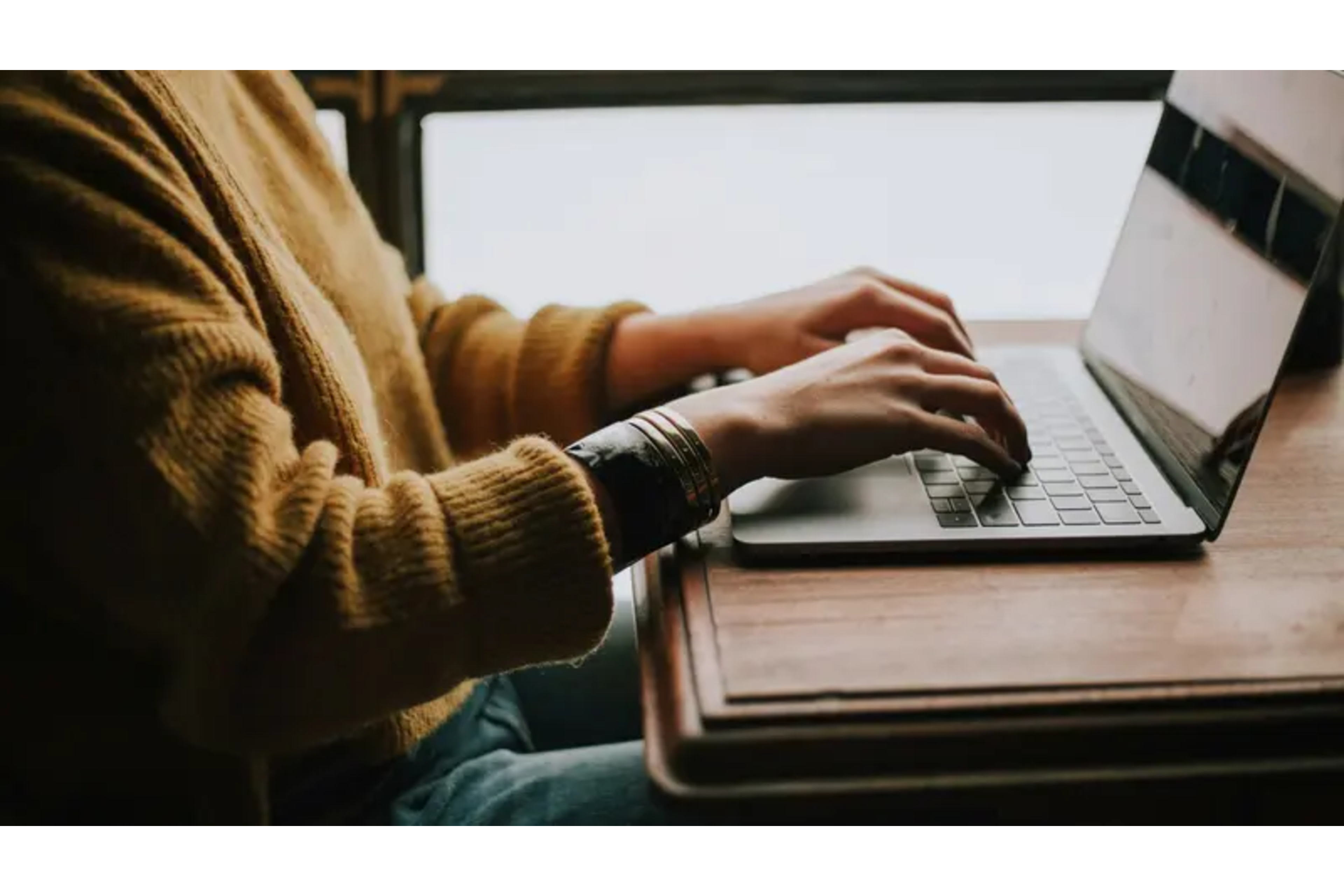 Hands typing on a laptop