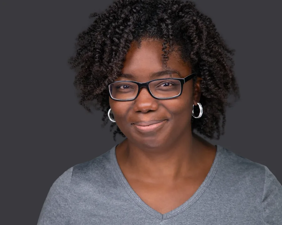 Retrato profesional de mujer con lentes en fondo gris para perfil de LinkedIn, marca personal y uso corporativo