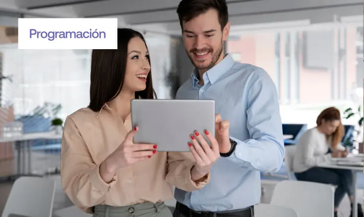 imagen de dos personas viendo contenido desde una tablet con una oficina de fondo