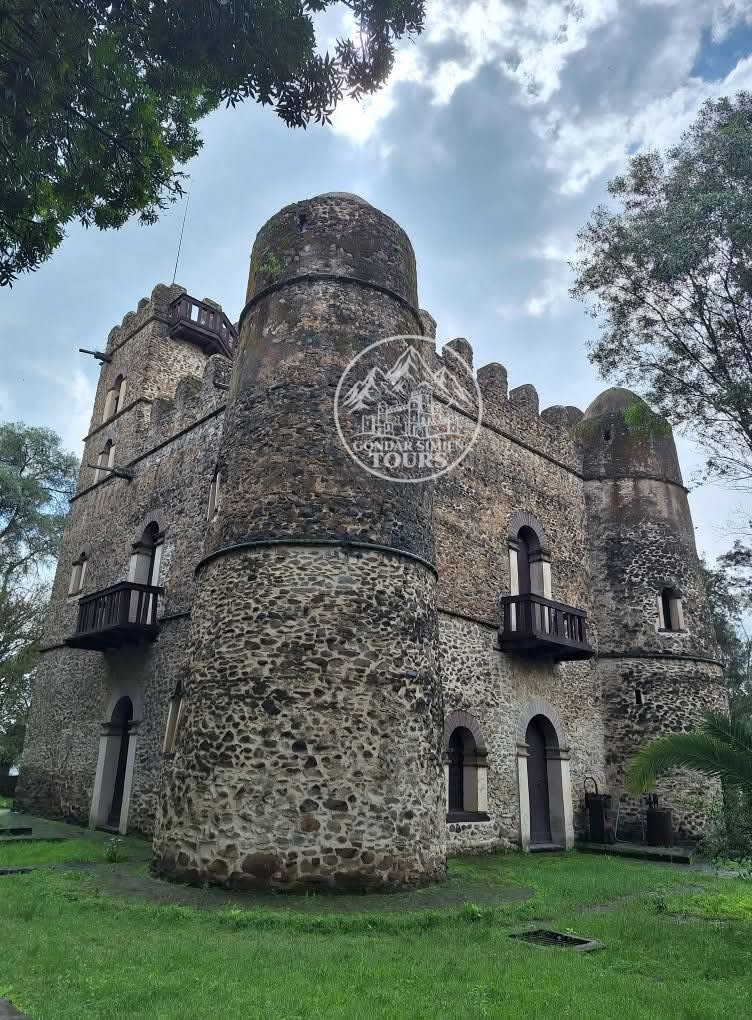 A stone castle with rounded towers beneath a cloudy sky
