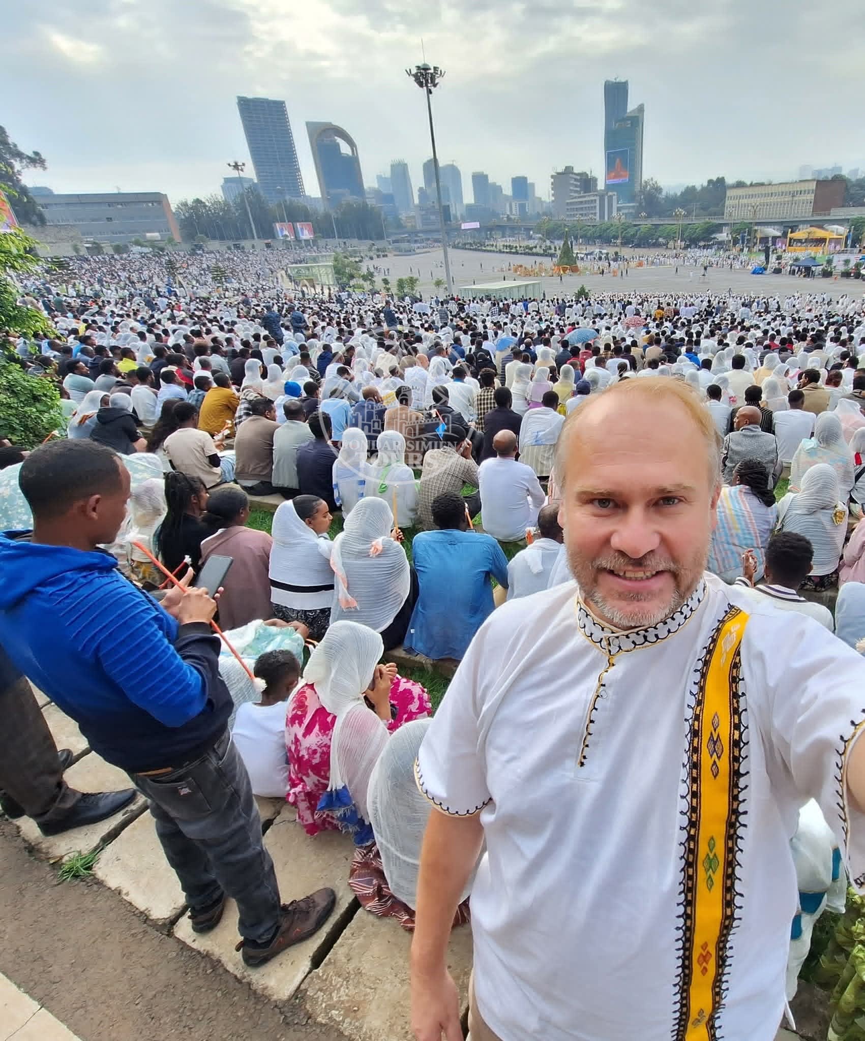 A visitor overlooking a large gathering in an urban square