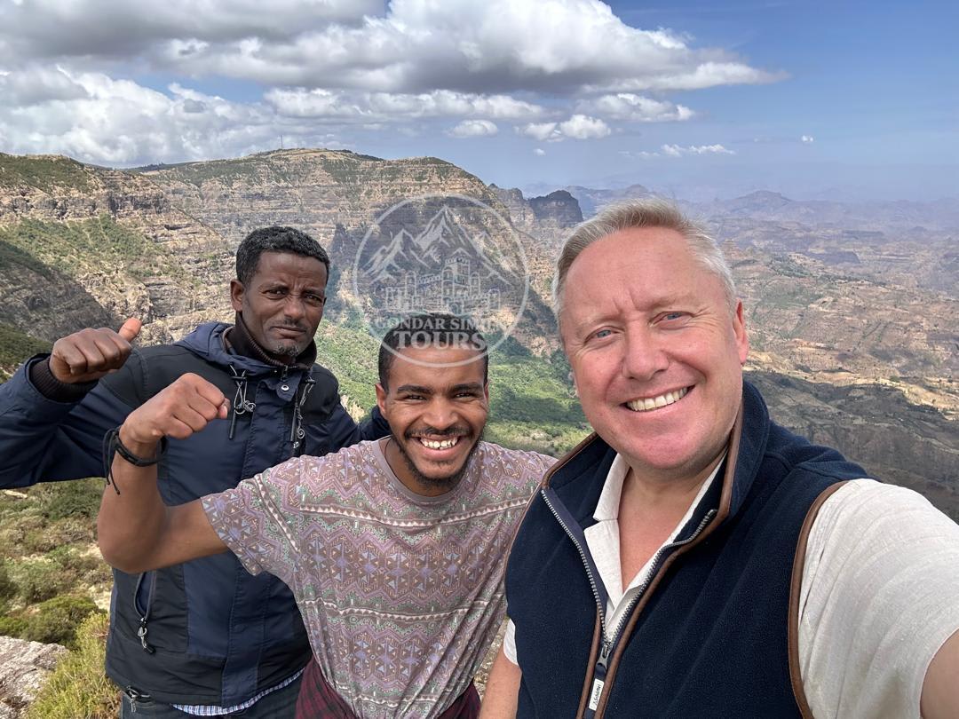 Three travellers taking a photograph together in the mountains