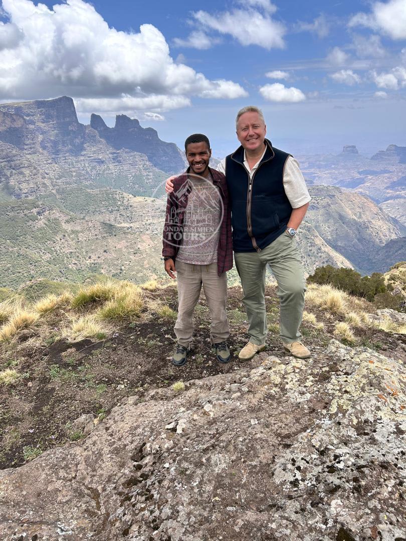 Two hikers posing on rocky ground above the Simien valleys