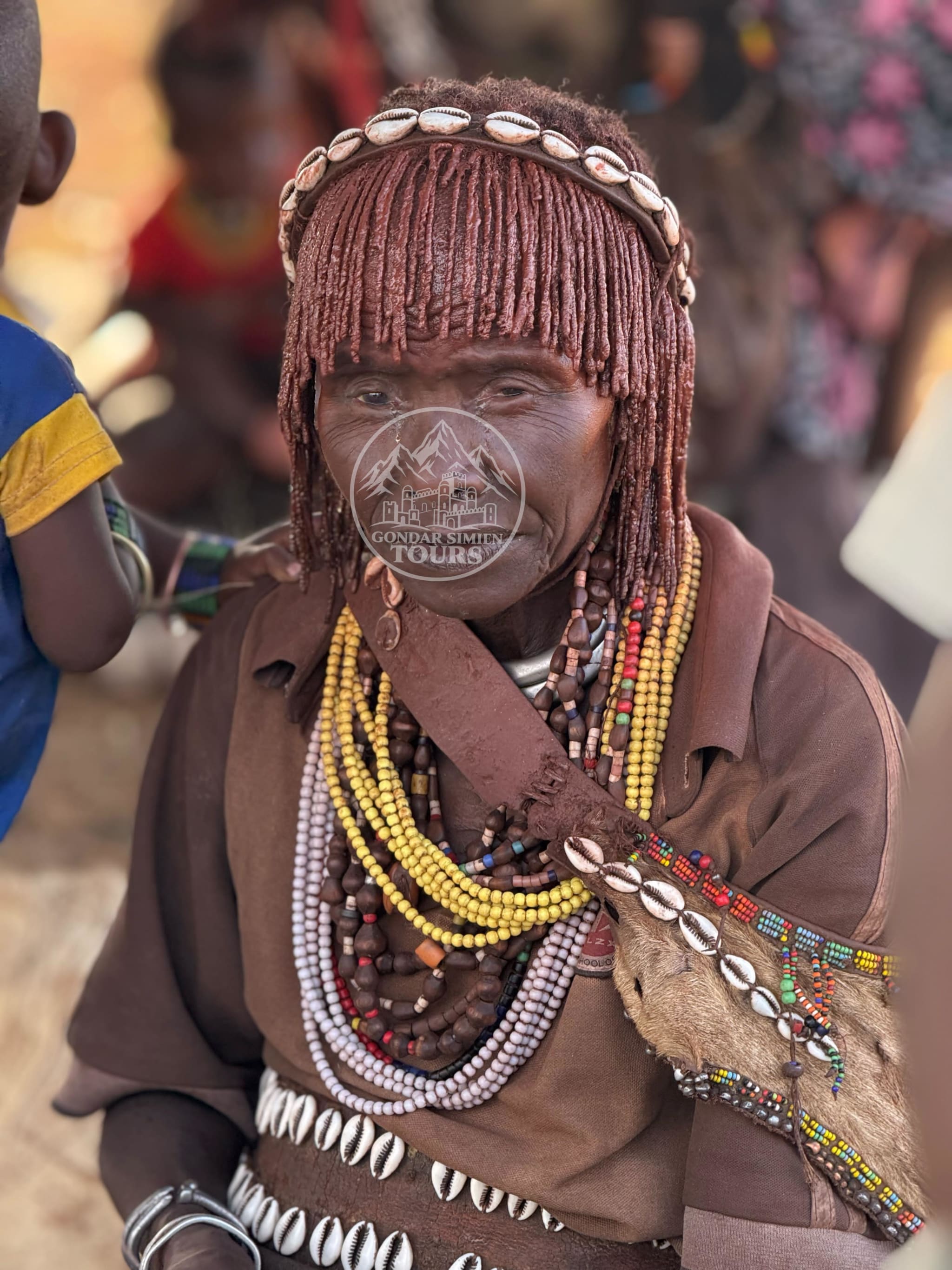 Portrait of a person with braided hair, beaded necklaces and a decorated headband