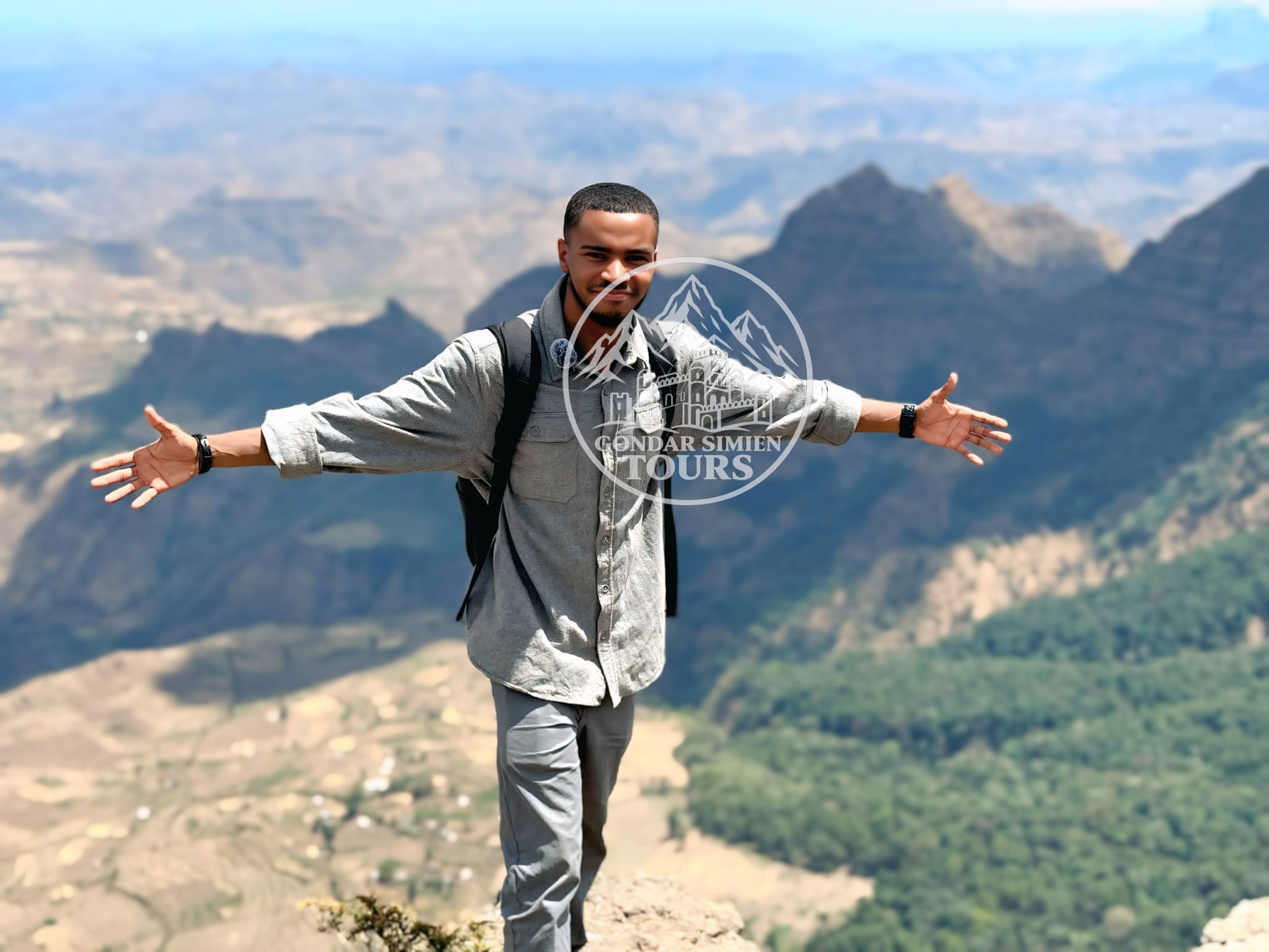 A traveller with outstretched arms above the Simien escarpment