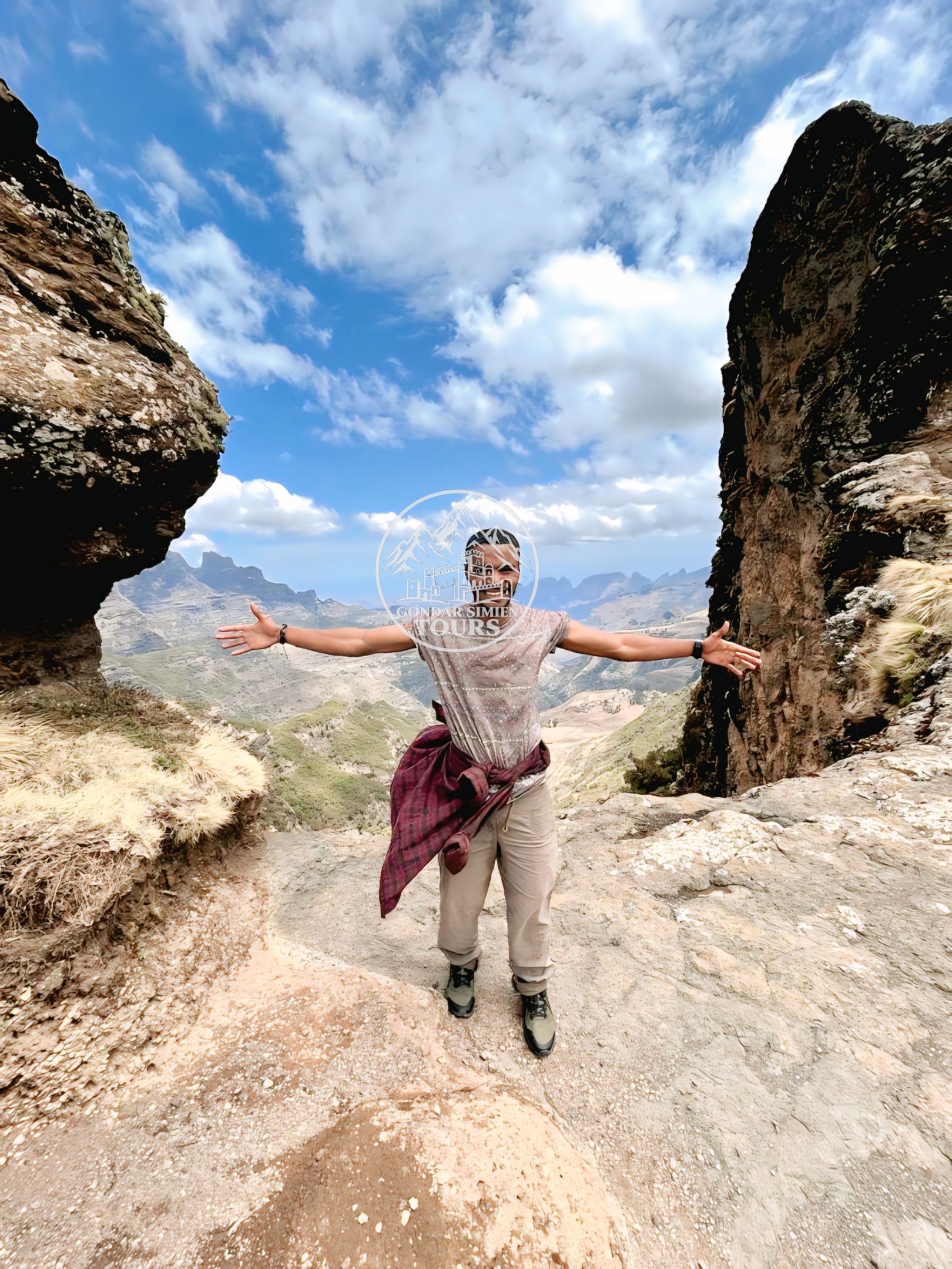 A hiker standing with open arms between tall rock formations