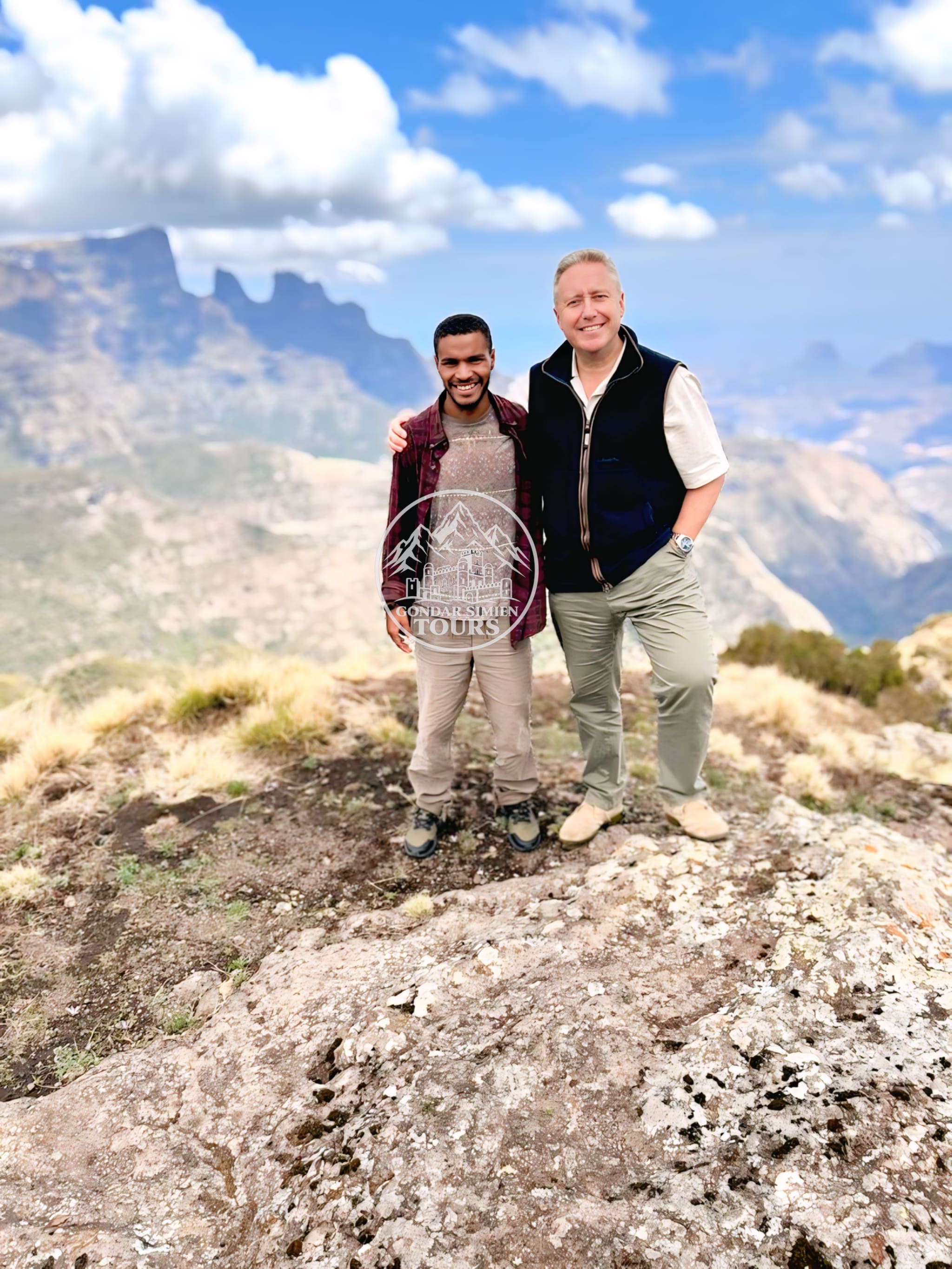 Two hikers standing together on a rocky mountain viewpoint