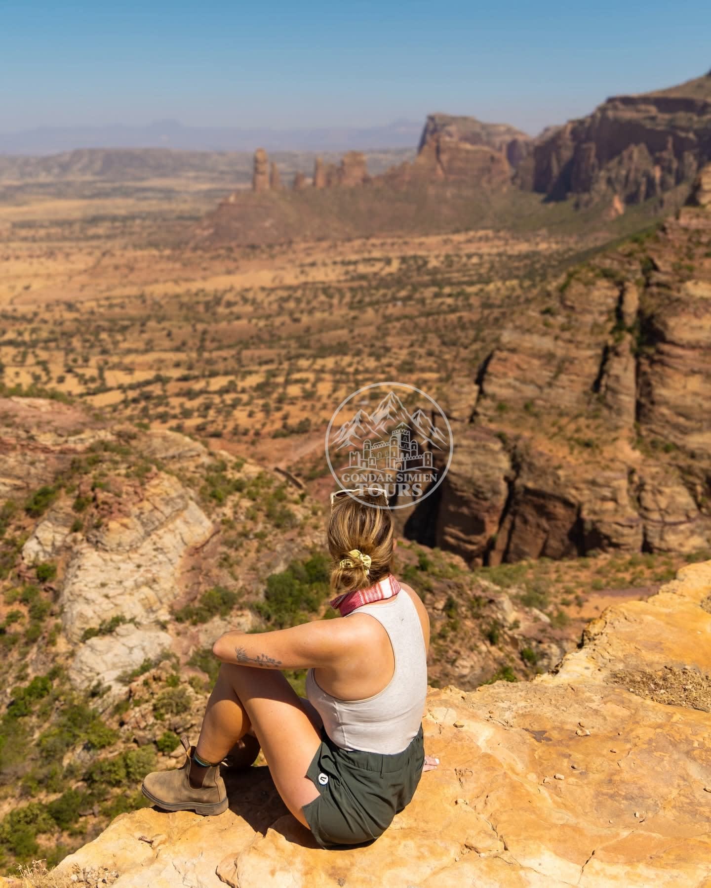 A traveller sitting on a rocky cliff edge above a canyon