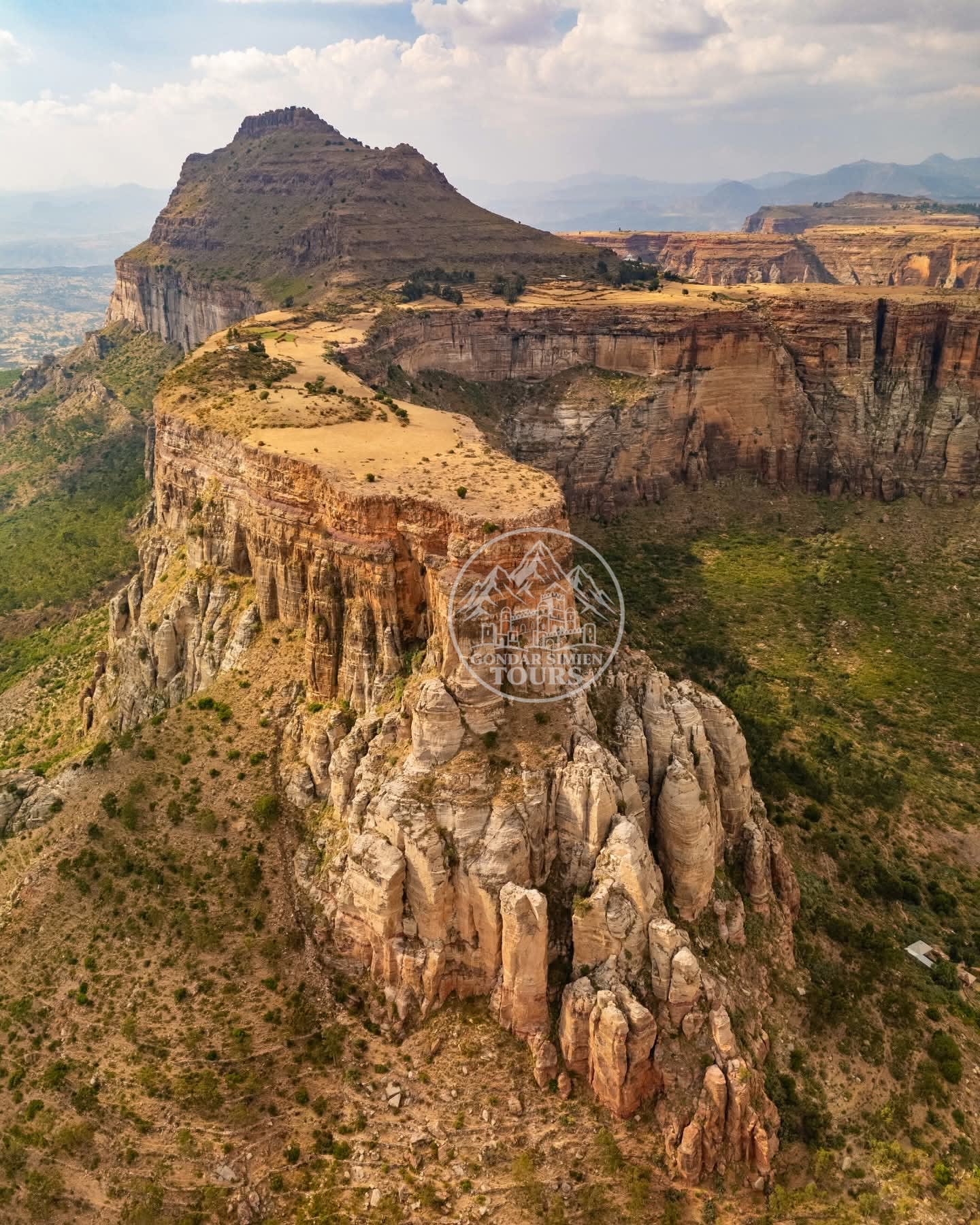 A flat-topped plateau ending in a sheer cliff above green valleys