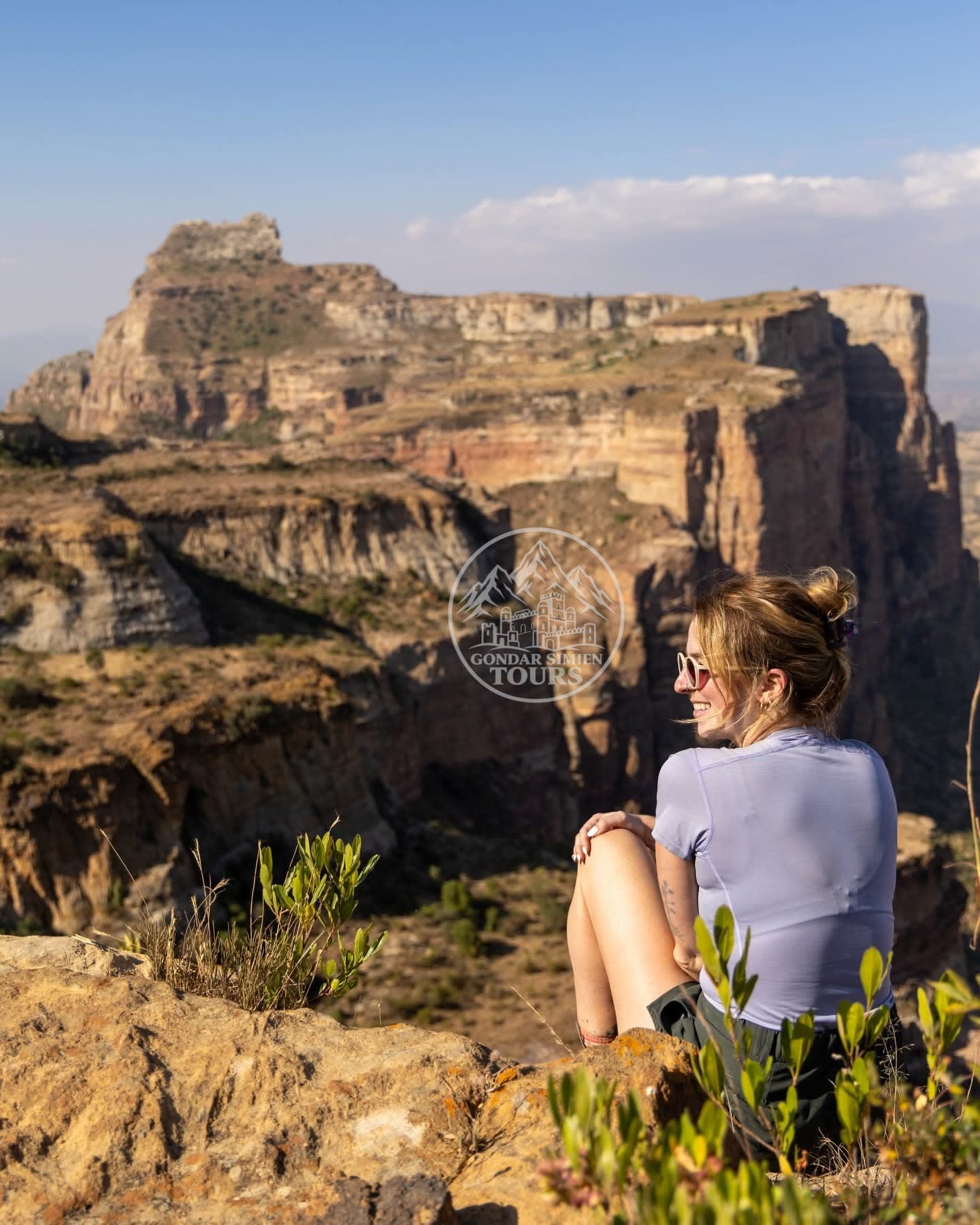 A traveller sitting on a rocky ledge above the Simien canyons