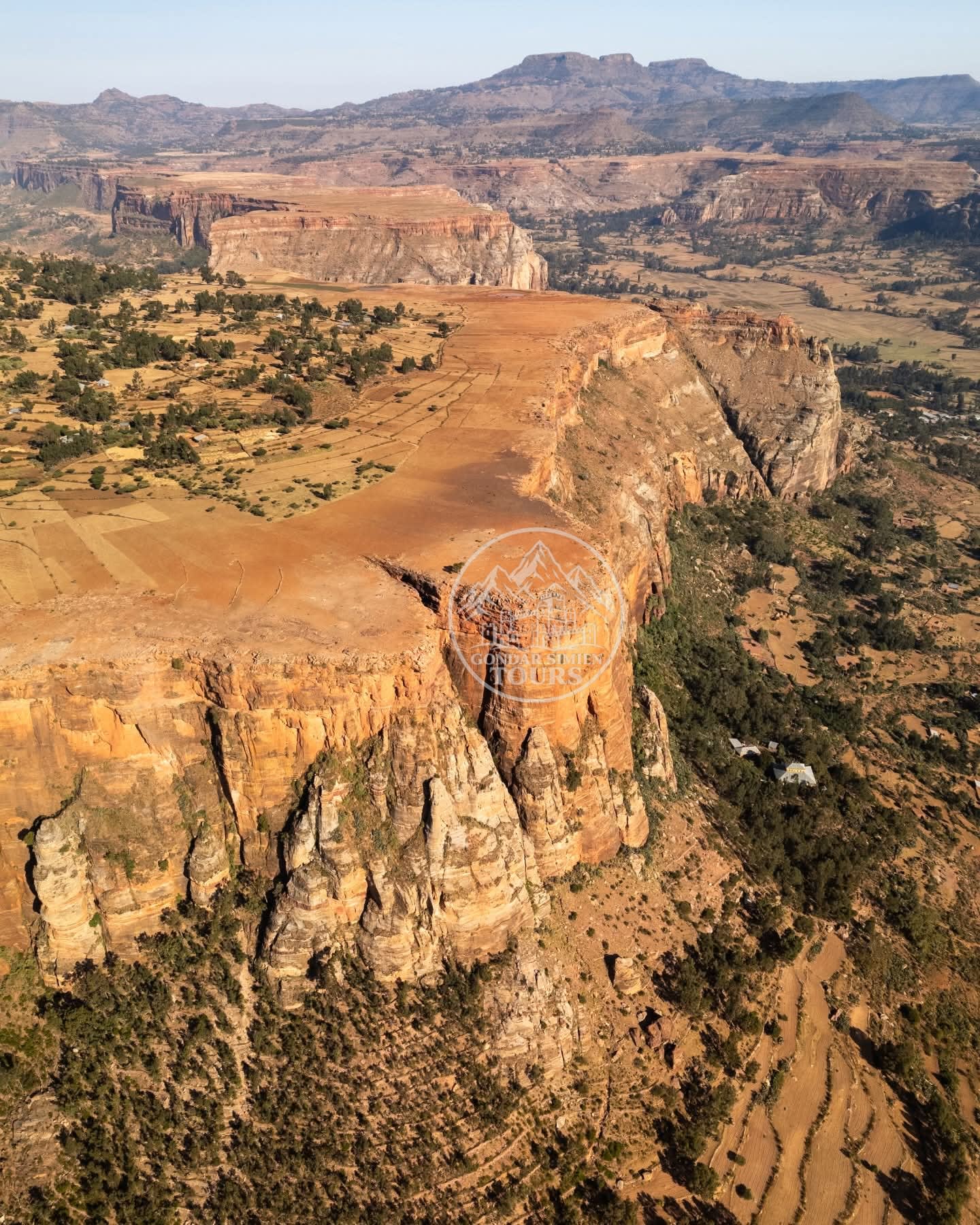 Sheer cliff pillars rising above a green valley settlement