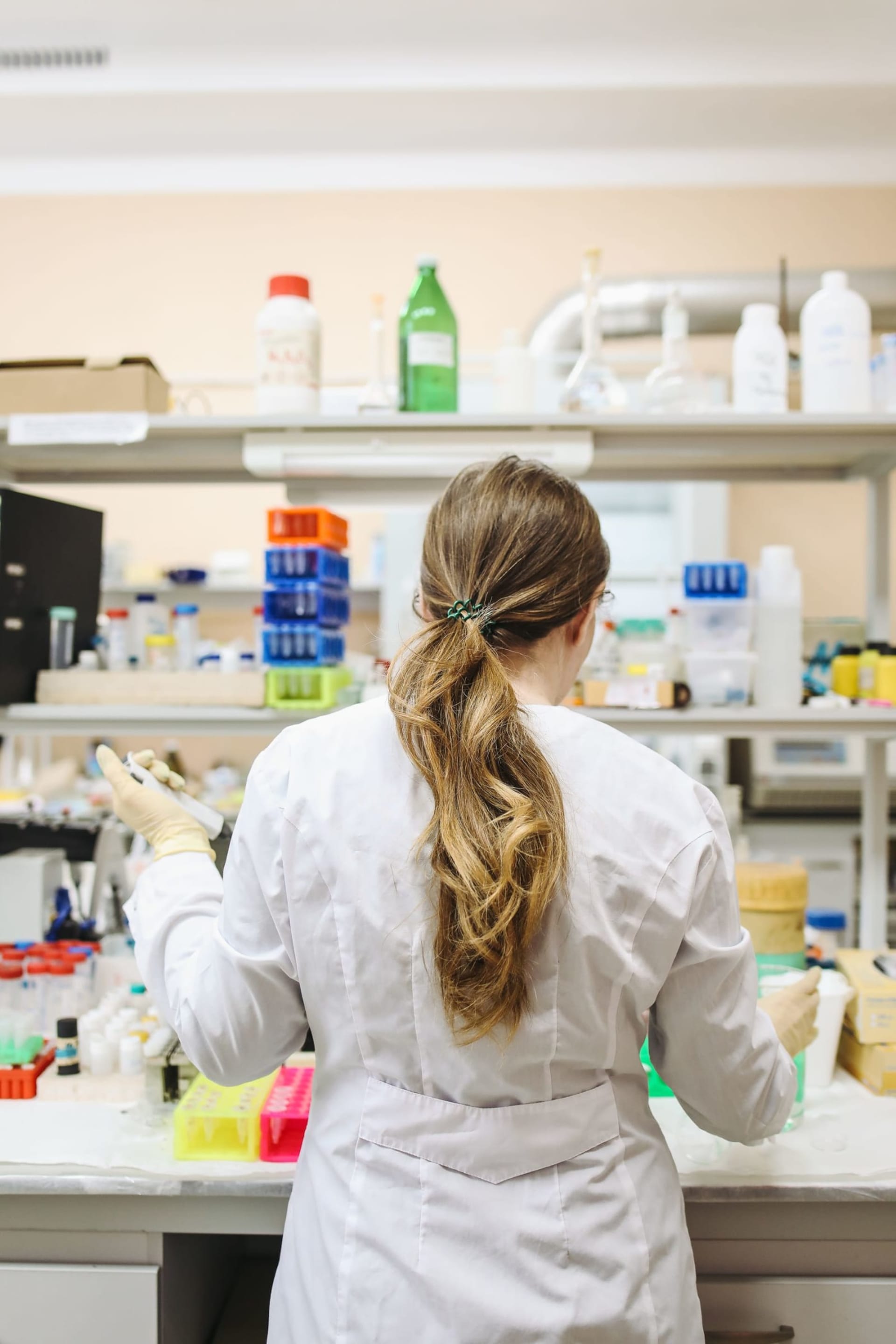 Scientist in a white coat working among laboratory equipment
