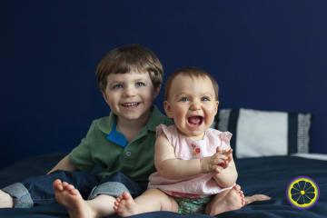 brother and sister smiling on bed in columbia mo