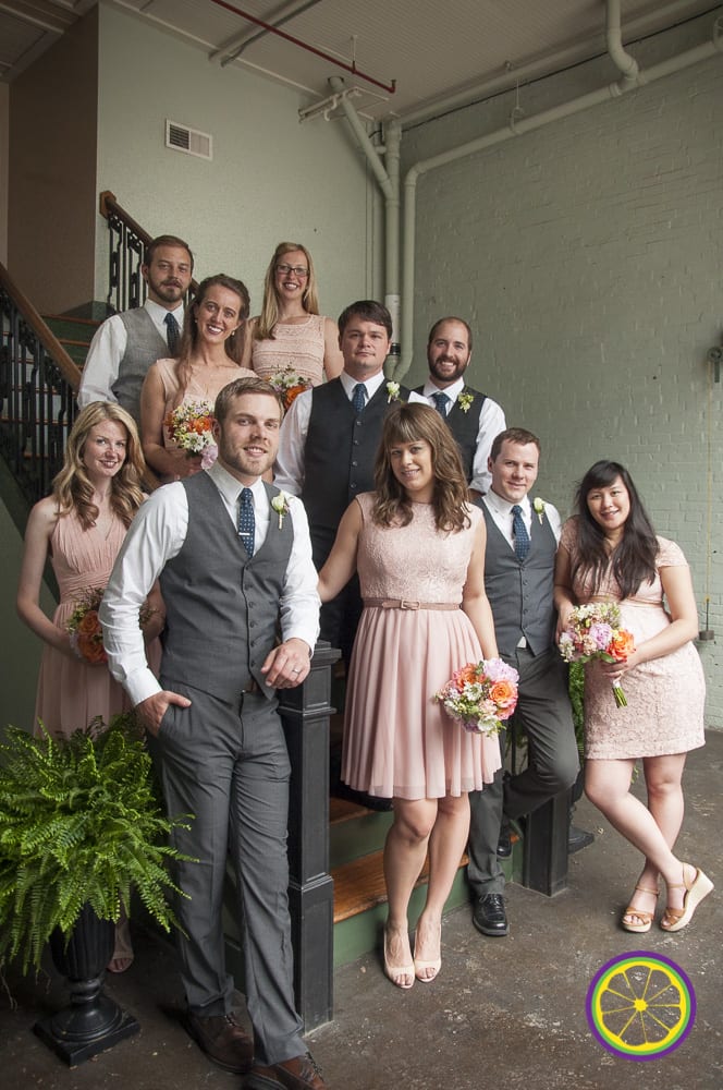 Wedding party portrait, with groomsment in vests and bridesmaids in pink dresses, holding flowers