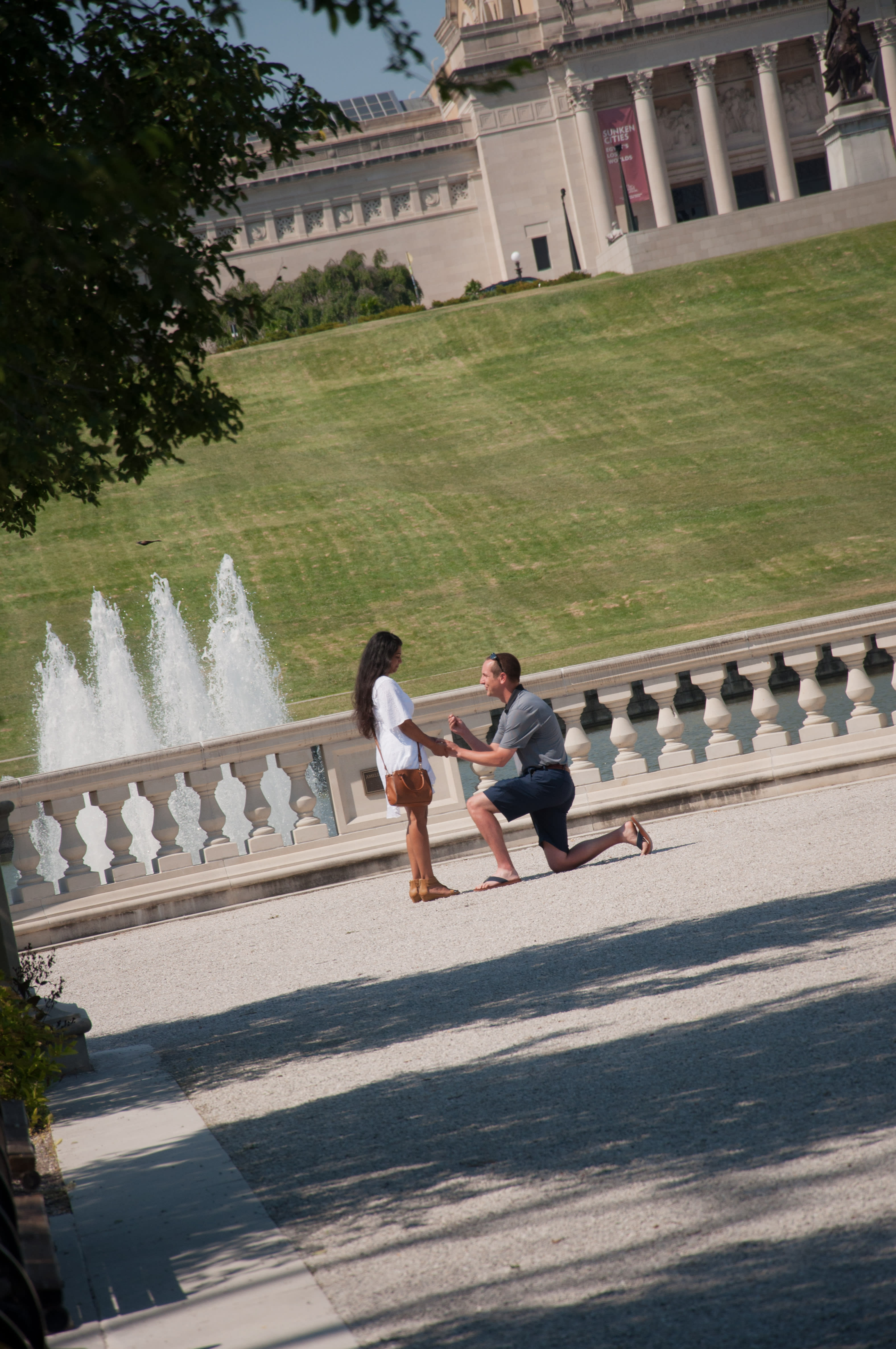 Multiracial couple during proposal for engagement in Forest Park Grand Basin near Art Musuem at Art Hill