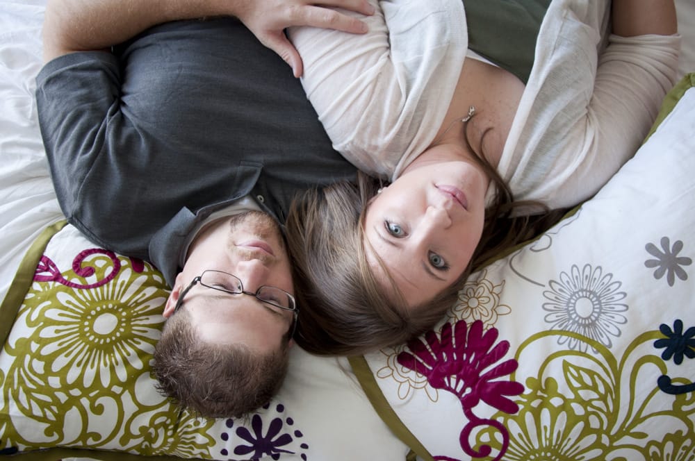 engaged couple snuggled on bed for upsidedown photo