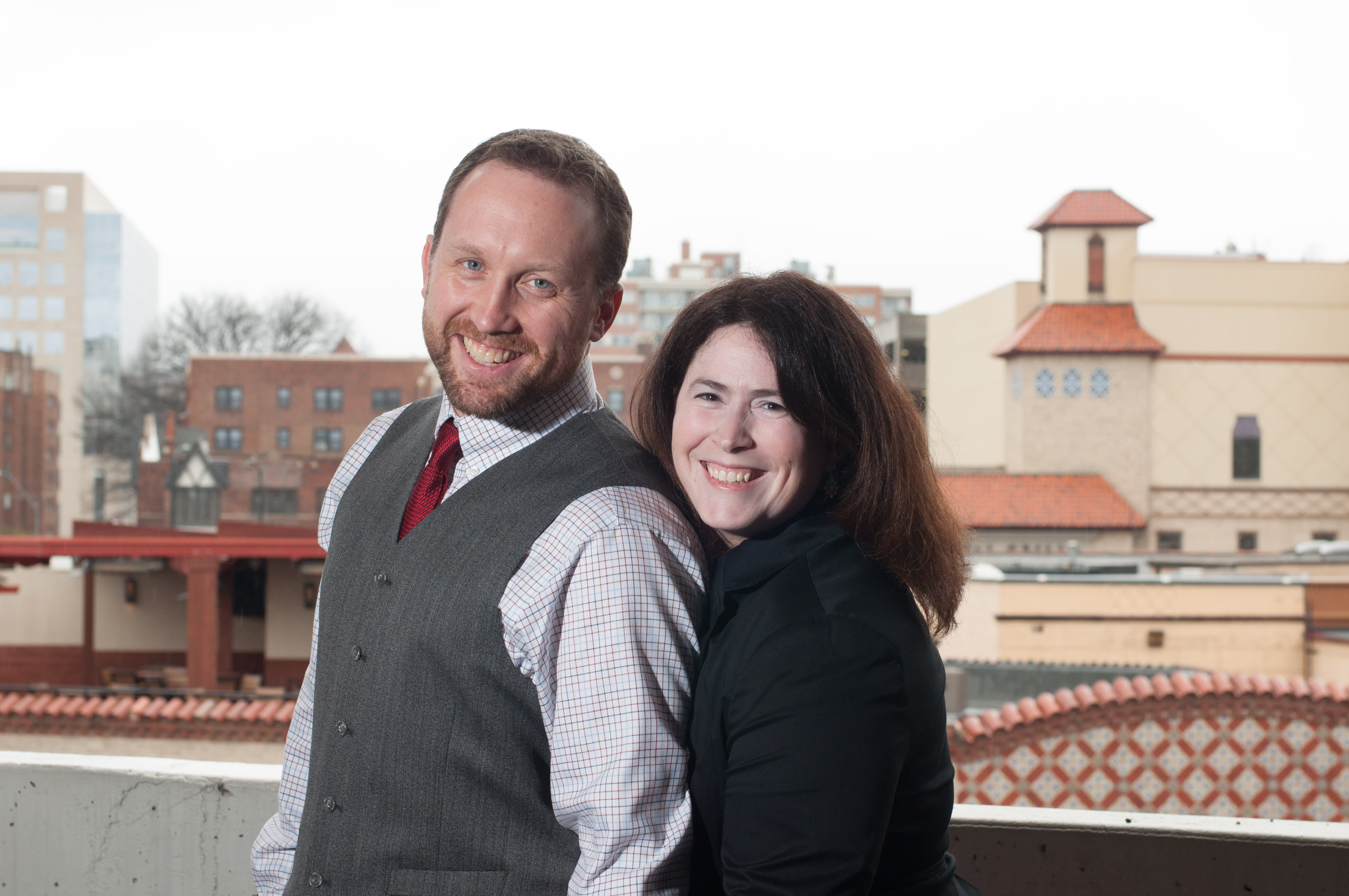 Couple in Kansas City MO photographed by plaza skyline with red roofs