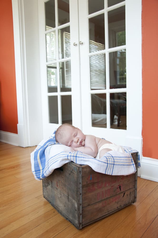 portrait of infant boy asleep in a weathered crate