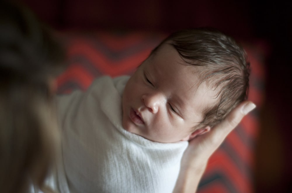 mother holding newborn baby boy swaddled in St. Louis MO