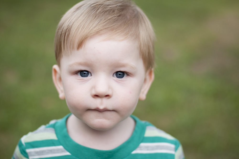 Toddler boy looking at camera for a picture in green