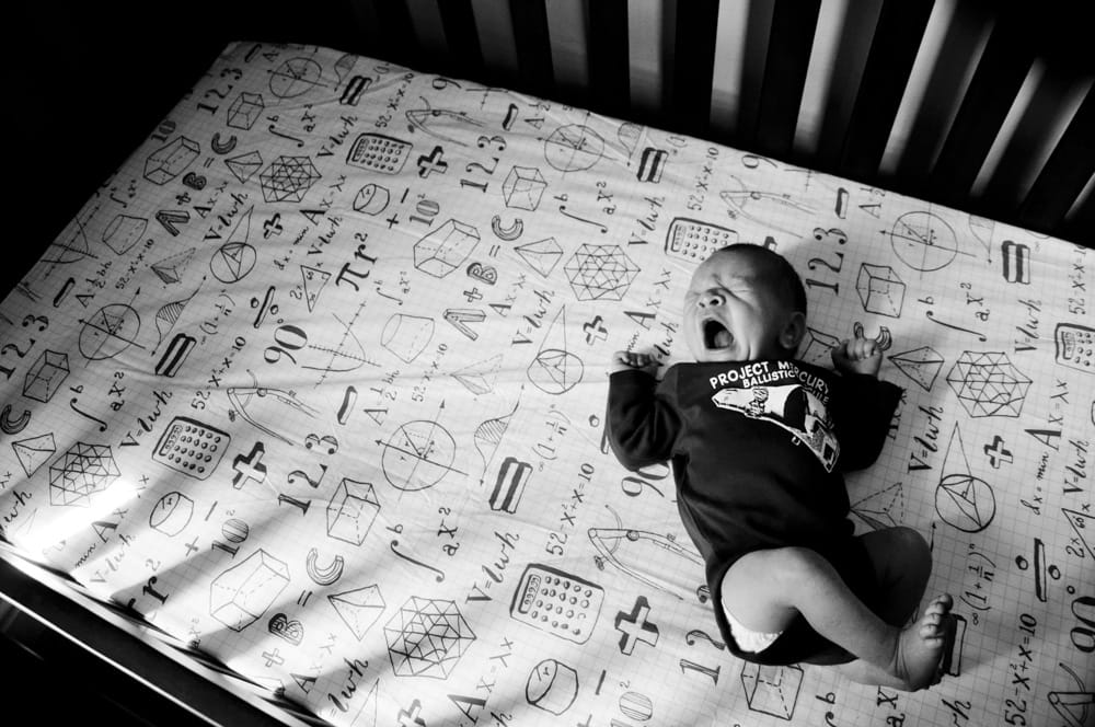 baby yawning in his crib with genius sheets in black and white in maplewood MO