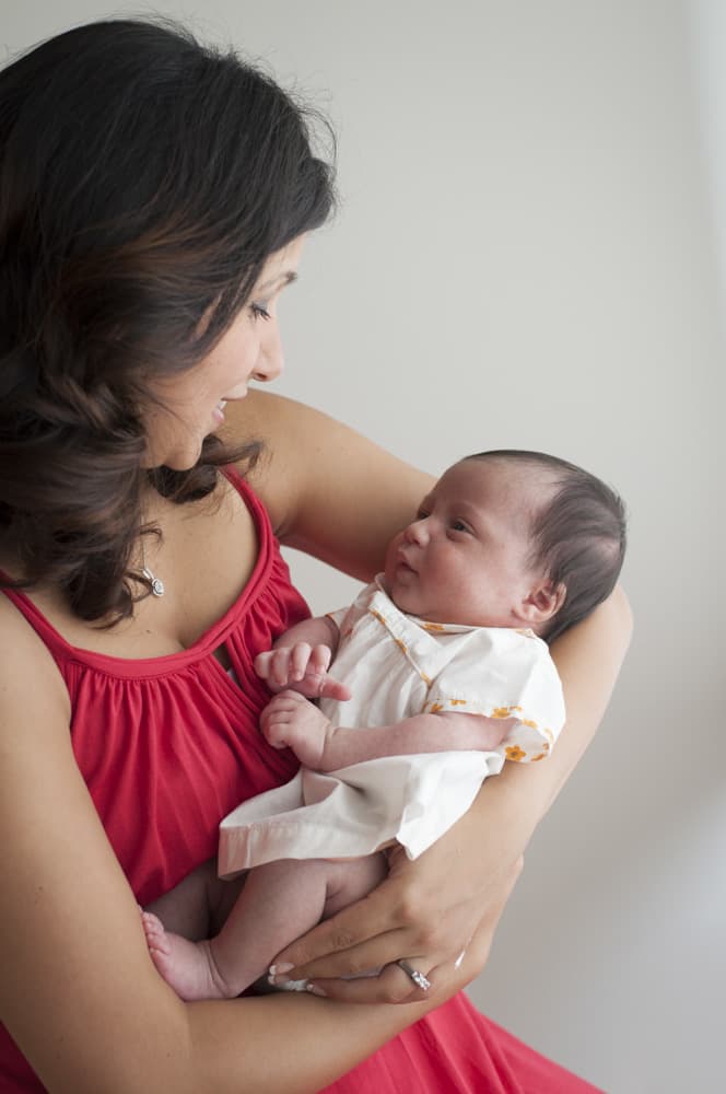 Mother holding newborn baby girl and looking at her