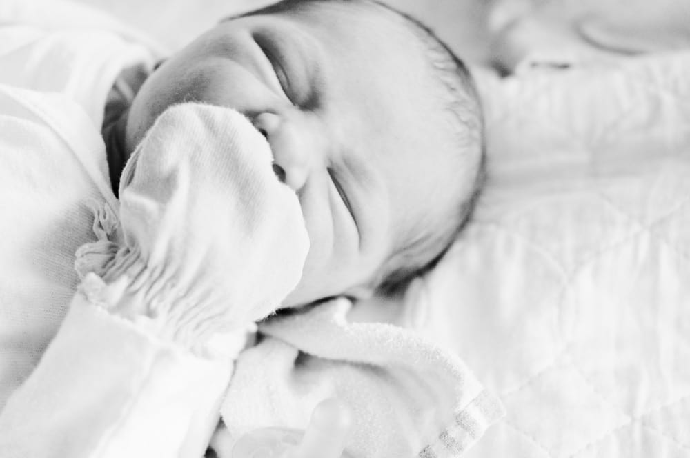 Newborn baby photograph with mittens and yawn in St. Louis hospital