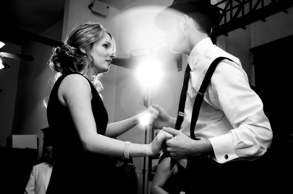 couple swing dancing at wedding reception with lense flare from flash in Lincoln IL