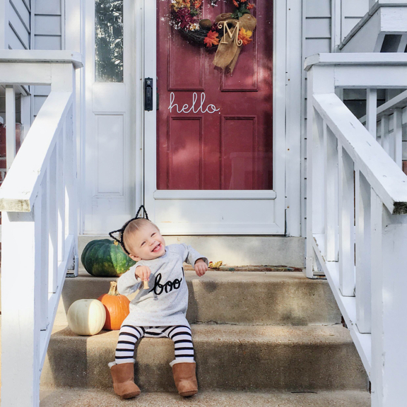 Rose sitting on the front porch steps next to some pumpkins