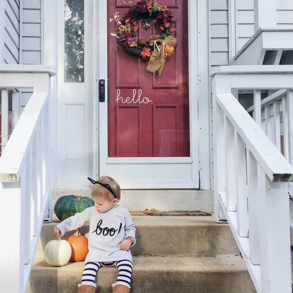 Rose sitting on the front porch steps next to some pumpkins