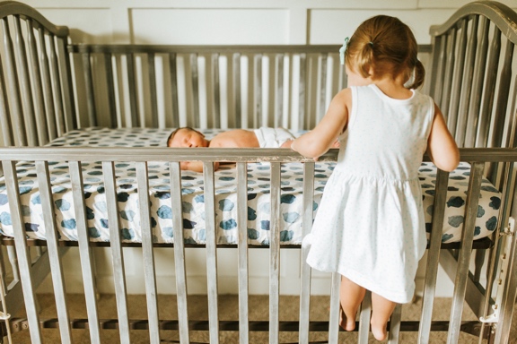 Rose standing on Kolbe's crib rail looking at him