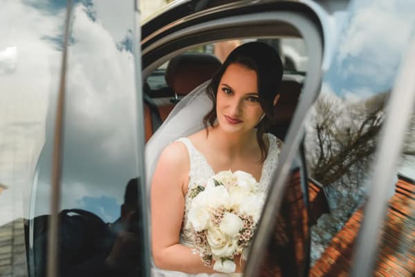 Panna młoda z bukietem w samochodzie w drodze na wesele