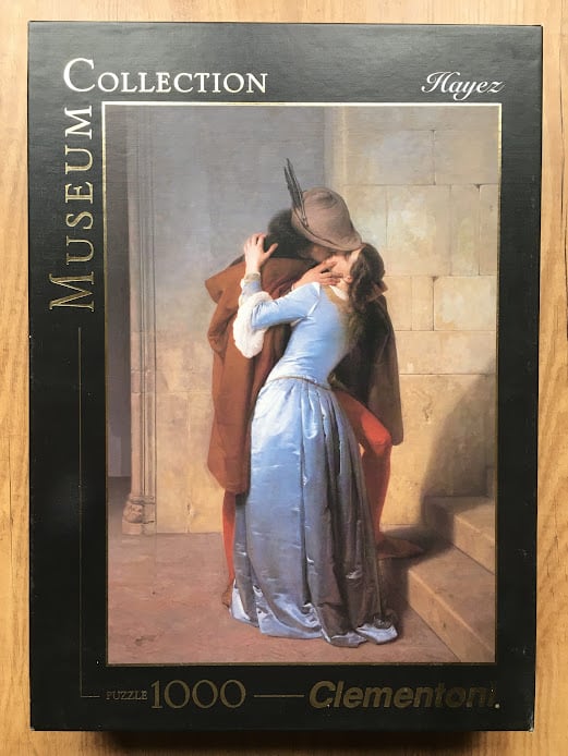 A reproduction of Francesco Hayez's The Kiss, showing a couple in medieval attire embracing on a stone landing.
