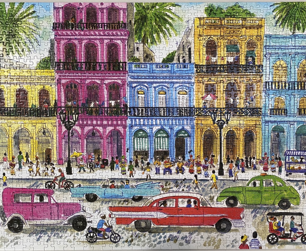 A vibrant street scene of colorful colonial-style buildings and vintage cars in Havana, Cuba.
