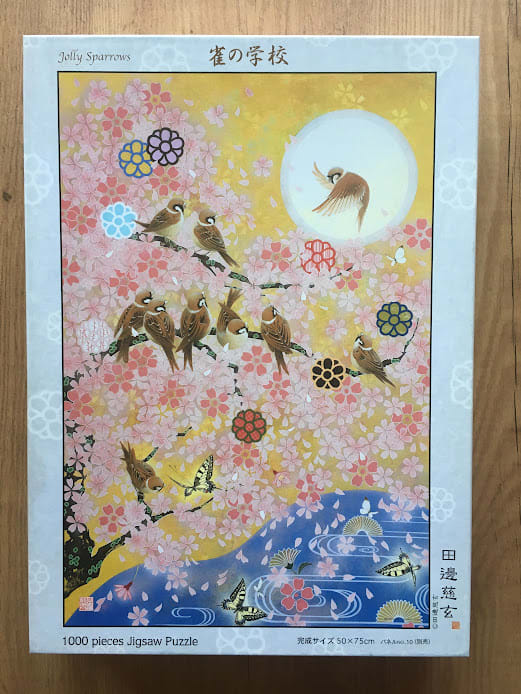 An illustration of small brown sparrows perched on cherry blossom branches against a golden moonlit background.