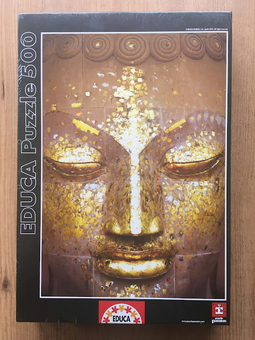 Close-up photograph of a golden Buddha statue face covered in gold leaf flakes