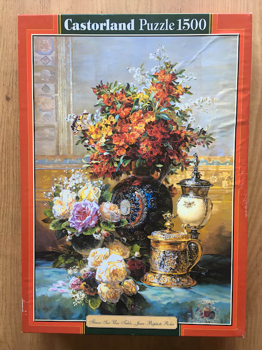 Still life oil painting featuring a large bouquet of orange flowers, assorted roses, and ornate antique metal vessels.