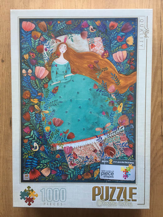 An illustration of a princess with long orange hair in a teal dress resting in a garden of colorful stylized flowers.