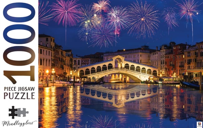 The Rialto Bridge in Venice illuminated at night under a vibrant firework display reflected in the Grand Canal.