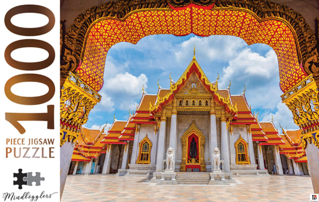 A low-angle, framed view of the Wat Benchamabophit temple in Bangkok under a bright blue sky.